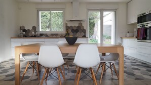 Una cocina moderna con una mesa de comedor de madera, dos sillas blancas y un suelo de baldosas hexagonales.