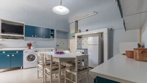 Ett kompakt kök med tvättmaskin, ett matbord med stolar och ett kylskåp.