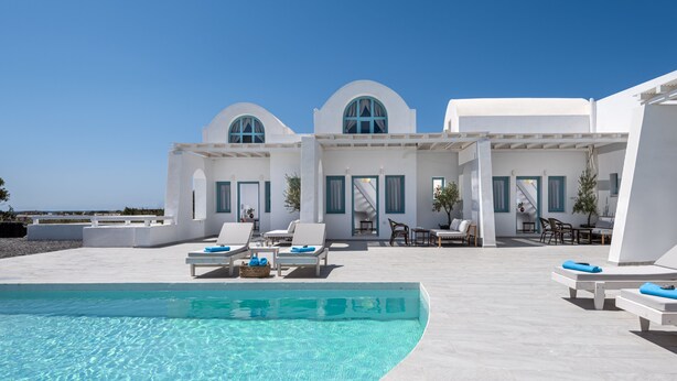 Ein Poolbereich mit Liegestühlen und freiem Blick auf das Meer.