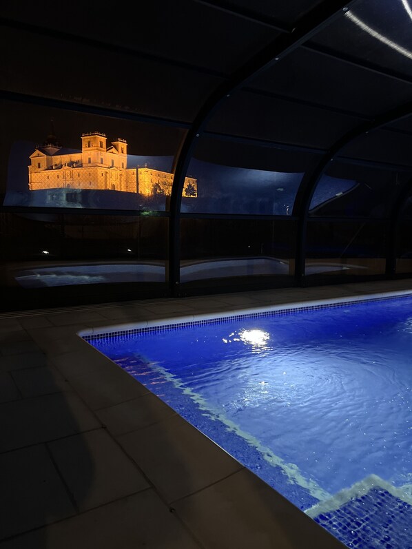Une piscine offrant une vue sur un bâtiment qui ressemble à un château, de nuit.