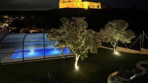 A castle-like building illuminated at night with a pool and trees in the foreground.