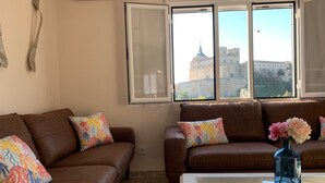 A living room with two brown leather sofas, colorful floral cushions, a white coffee table, and a vase with flowers.