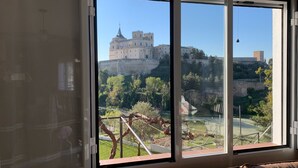 A room with a large window overlooking a castle and a garden.