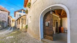 Una estrecha calle adoquinada con un edificio de fachada de piedra, un arco de entrada y una puerta de madera.