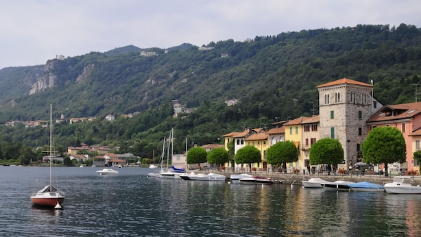 Un pueblo a orillas del lago con barcos amarrados, una torre destacada y edificios a lo largo de la costa.