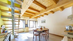 Una cocina amplia con vigas de madera, un comedor con sillas y una escalera en espiral.