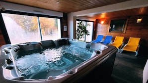 A hot tub area with seating and a view of the outdoors. - Gîte Mélina with Spa Jacuzzi Sauna Fishing pond (Dommartin-lès-Remiremont)