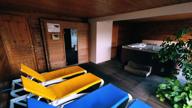 Una habitación con paredes de madera, una bañera de hidromasaje y una pequeña zona exterior con un banco.