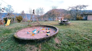 A playground with a swing set, a slide, and a sandbox with toys.