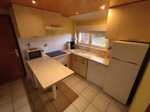 Eine kleine Küche mit Mikrowelle, Herd, Spüle und Kühlschrank.