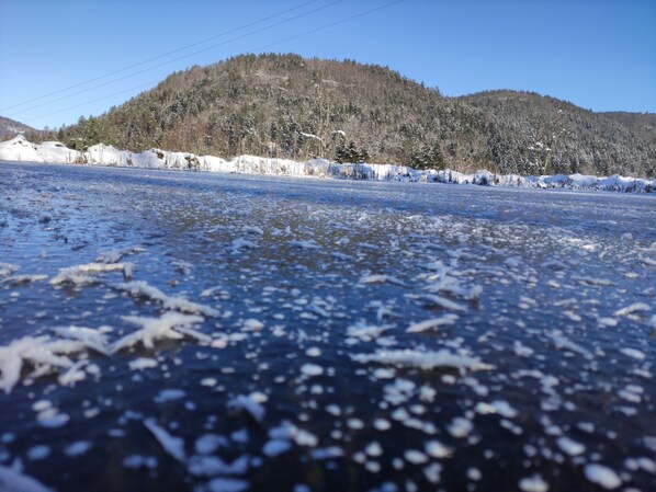 A snowy landscape with a clear sky and a hill in the background.