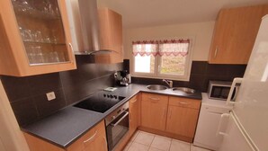 Una cocina compacta con estufa, fregadero y microondas.