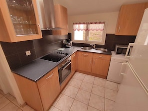 A compact kitchen with a stove, sink, and microwave.