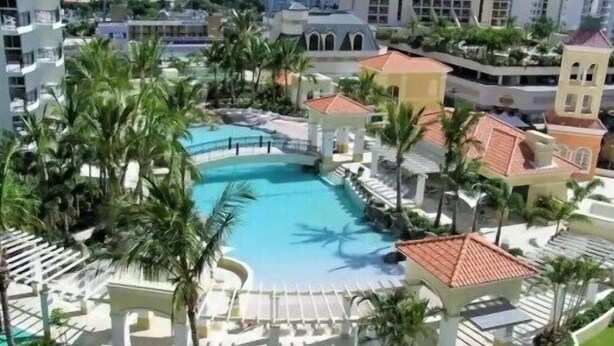 A resort with a central swimming pool surrounded by palm trees and lounge areas. - Chevron Renaissance, 2BR w/ Views, Parking & WIFI (Gold Coast)