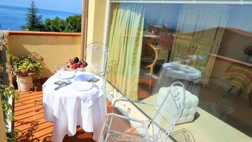Une table dressée pour deux personnes sur une terrasse avec vue sur la mer.