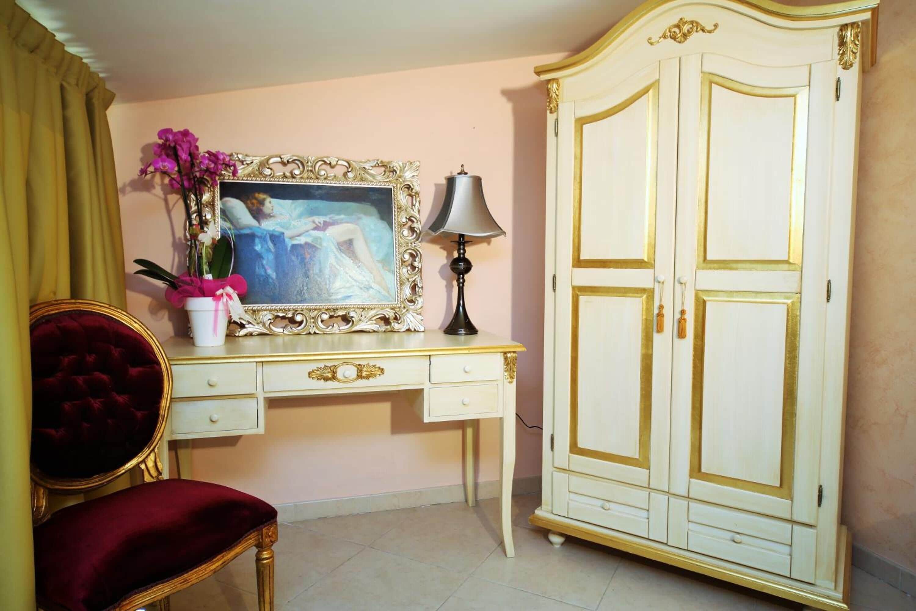 Una habitación con escritorio, silla, armario y un cuadro.