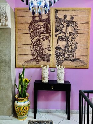 Una habitación con una pared morada, una consola negra y una planta decorativa en un jarrón amarillo.