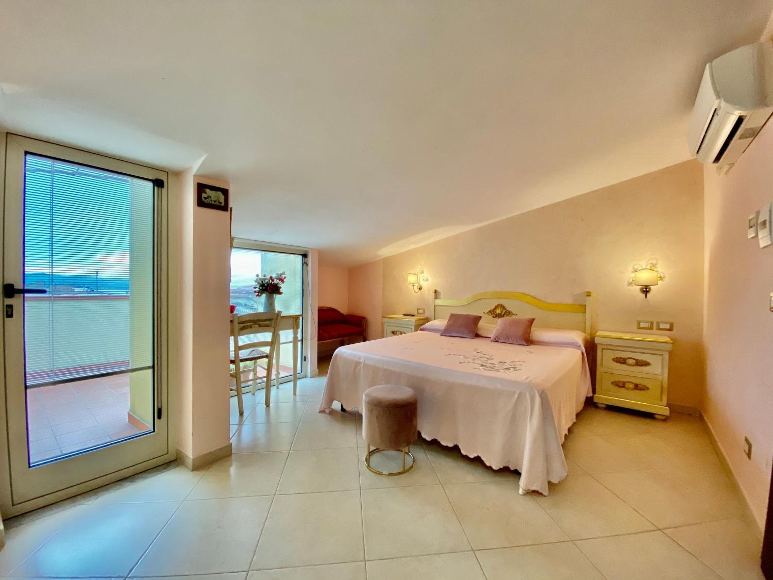 A bedroom with a bed, bedside tables, a chair, and a view through a door.