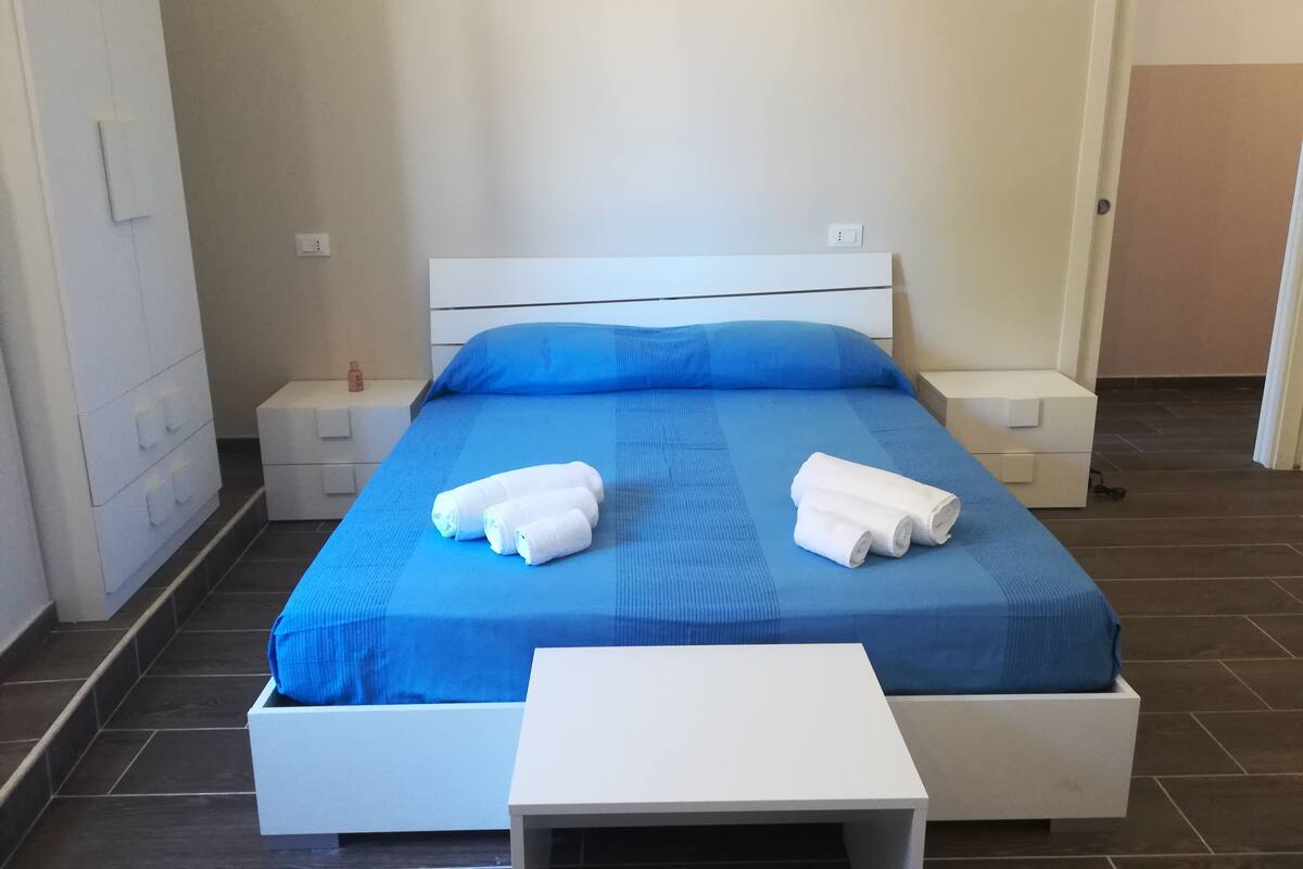Une chambre d’hôtel avec un lit, deux tables de chevet et une petite table blanche.