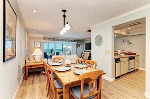 A dining area with a wooden table and chairs, a chandelier, and a view of the outside.