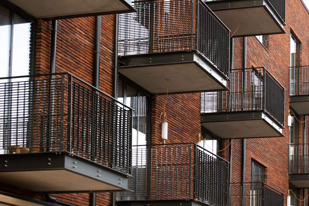 Un edificio de varios pisos con fachada de ladrillo, balcones metálicos y ventanas grandes.