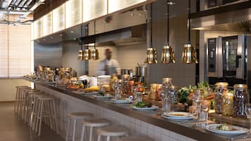 Une cuisine moderne avec un long comptoir, des tabourets et des luminaires suspendus.