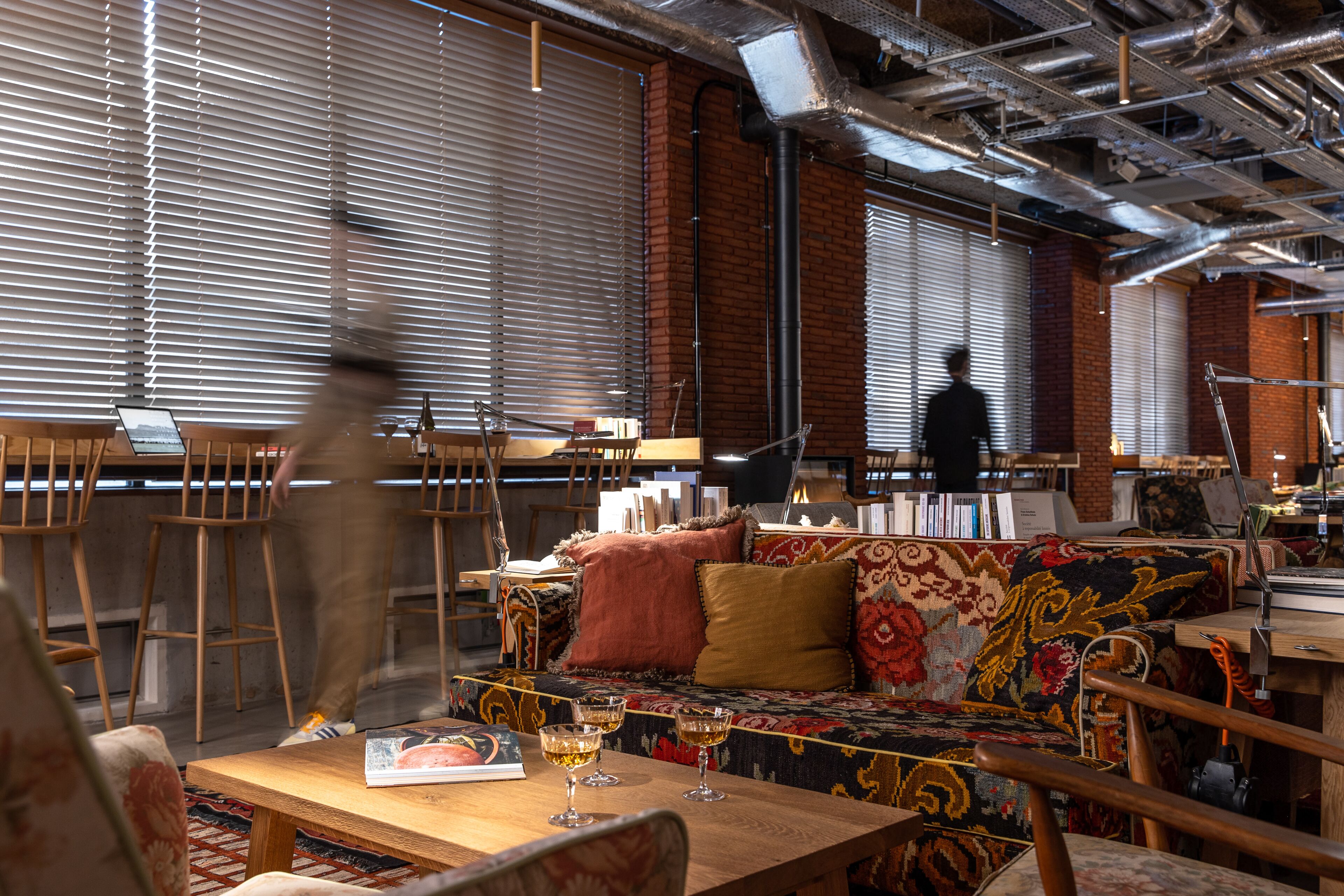 Un interior moderno con una mesa de madera, taburetes de bar y un sofá estampado.