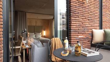 A modern hotel room with a cozy seating area, a dining table, and a view through a glass door.
