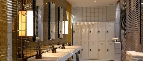 A modern bathroom with two sinks, mirrors, and a row of lockers.