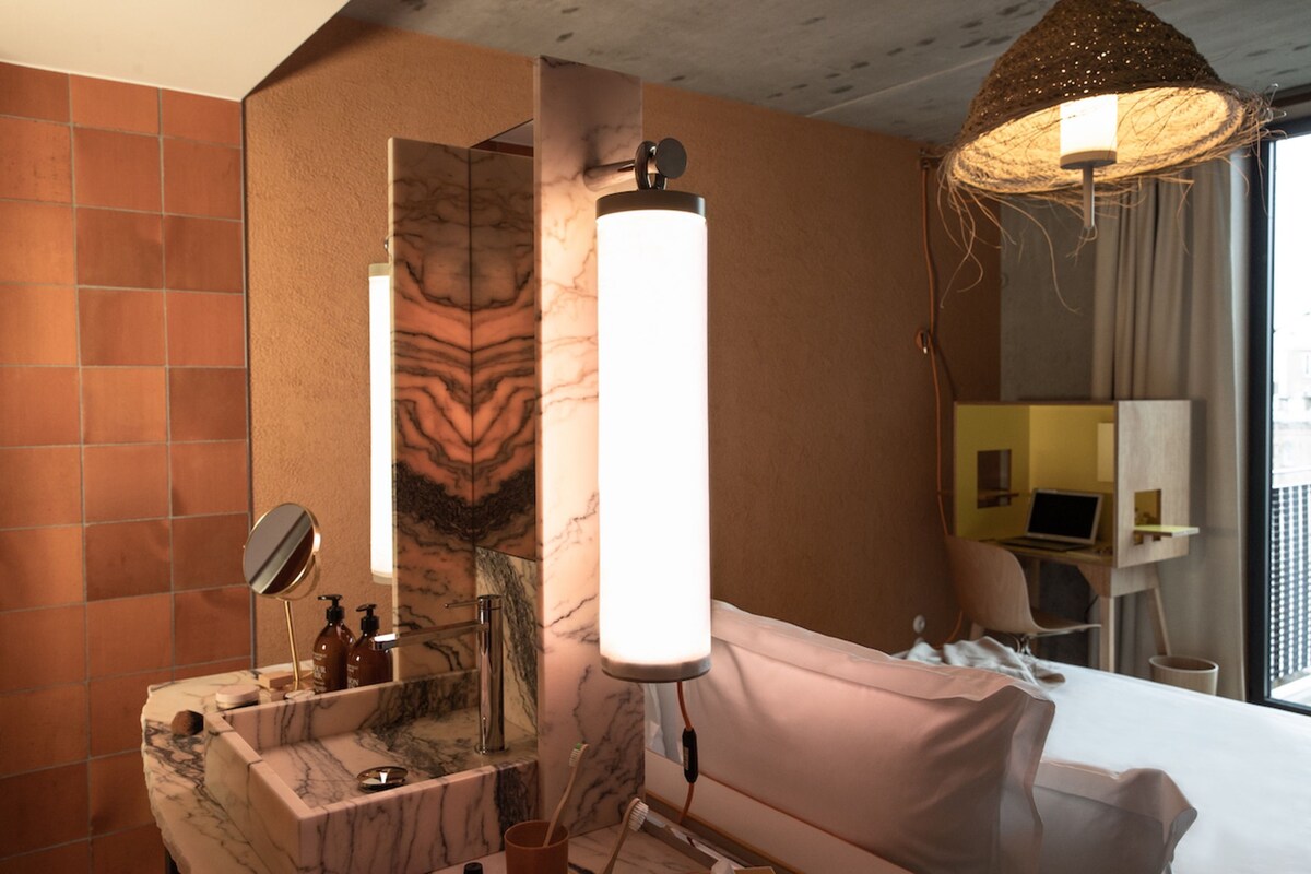 Een moderne badkamer met een marmeren wastafel, een spiegel, een handdoekrek en een douche.