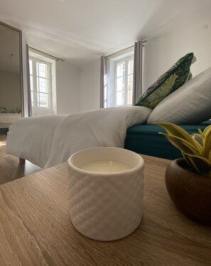 A bedroom with a bed, a bedside table with a candle, and a window with curtains. - Maison Saint Louis (Poitiers)