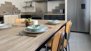 A modern kitchen with a wooden dining table set for four, including plates, cutlery, and a potted plant. - Maison Saint Louis (Poitiers)