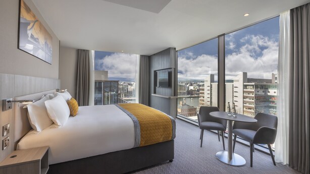 A modern hotel room with a large bed, a TV, a small table with chairs, and a city view through large windows. - The Samuel Hotel, Dublin City Centre (Dublin)