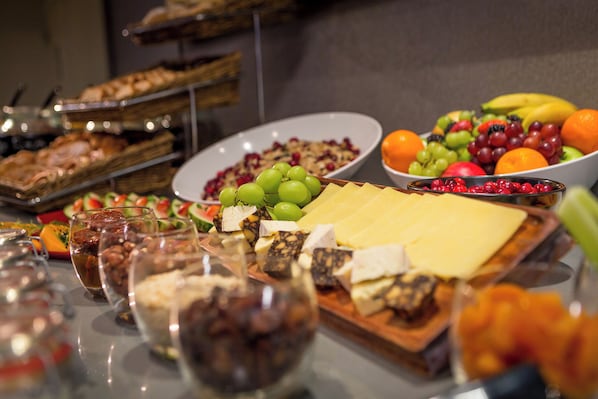 A buffet with various food items including fruits, cheeses, and breads.