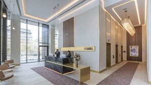 A modern reception area with a reception desk, seating, and a large window offering a view of the city. - The Samuel Hotel, Dublin City Centre (Dublin)