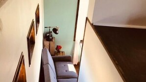 A staircase leading to a living area with a sofa and a lamp. - Grinnell Heritage Tiny House - On Organic Farm (Grinnell)