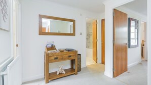 Un corridoio con un tavolo consolle in legno, uno specchio e una porta che dà su un bagno.
