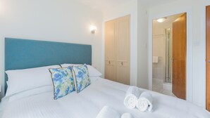 Una camera d'albergo con un letto, una testiera blu, un armadio in legno e uno spazio doccia.