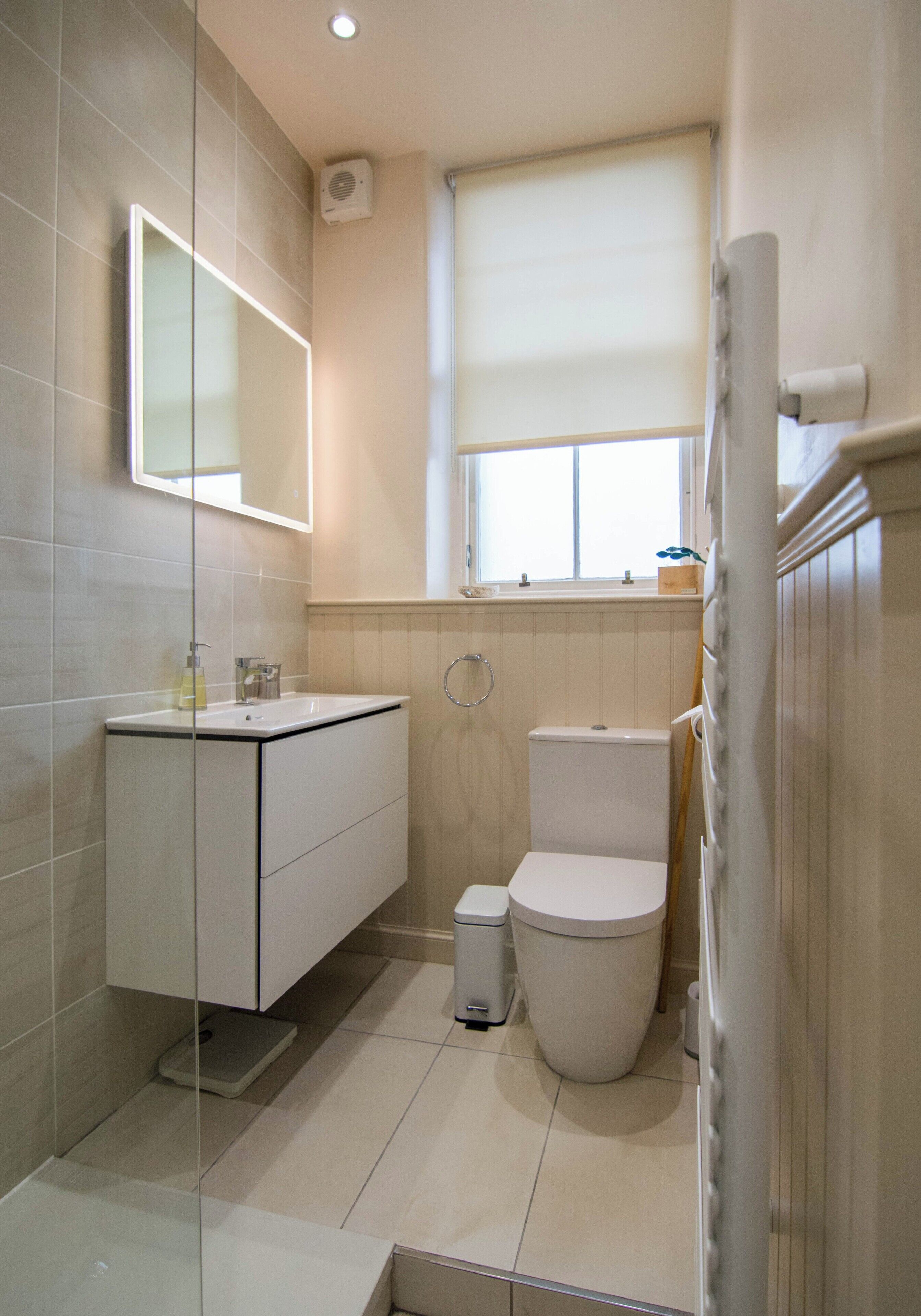 Un baño pequeño y moderno con inodoro, lavamanos y ducha.