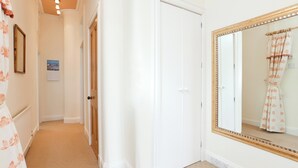 Ein Flur mit einer wei ßen Tür, einem großen Spiegel und einem gerahmten Bild an der Wand.
