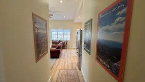 Un couloir orné de tableaux encadrés, un coin repas avec une table et des chaises, et un réfrigérateur.
