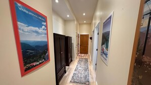 Un couloir orné d’une affiche représentant Warm Springs, en Virginie, avec une armoire en bois, un tapis à motifs et une porte en bois au fond.
