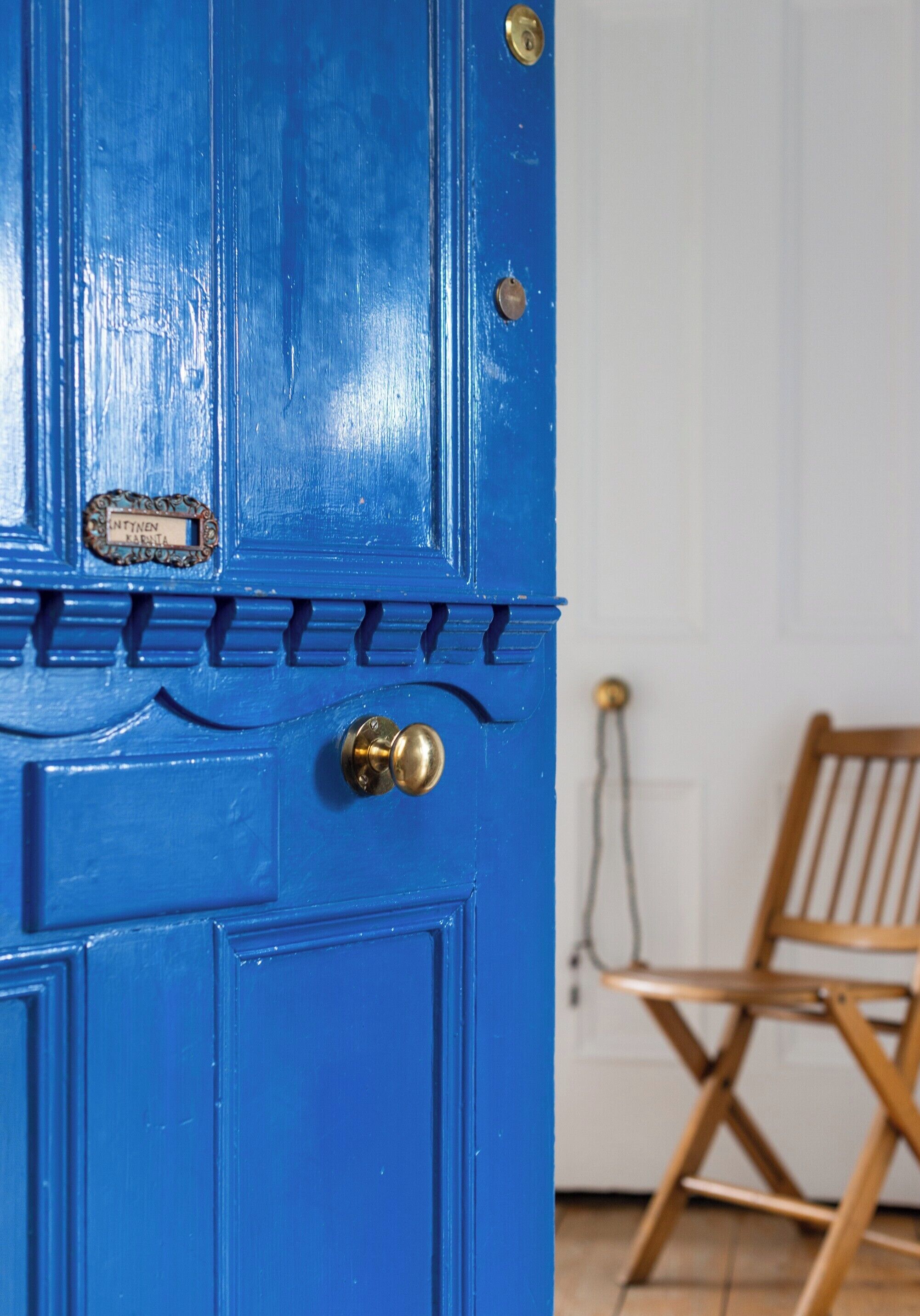 A blue door with a brass doorknob and a nameplate.