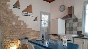 Una cocina con encimera azul, armarios blancos, pared de piedra y un reloj en la pared.