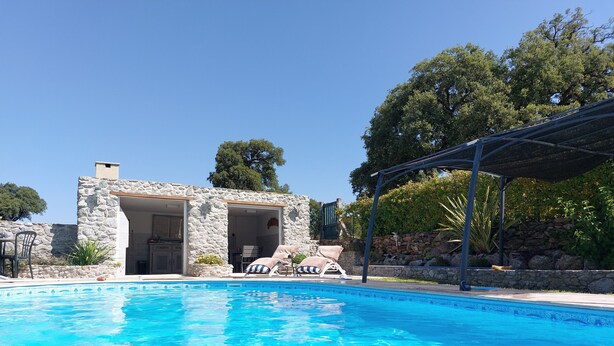 A pool with clear blue water, a stone building with an open doorway, and a covered patio area. - -Bright villa, pool, air conditioning, near St-Florent- sleeps 6 (Oletta)