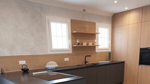 A modern kitchen with a central island, wooden cabinets, and a built-in oven. - -Bright villa, pool, air conditioning, near St-Florent- sleeps 6 (Oletta)