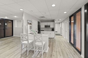 Una cocina moderna con armarios blancos, una isla central con asientos y un microondas sobre el fregadero.
