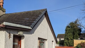 Einbungalow mit schrägem Dach, einer Holztür und einem kleinen Fenster.