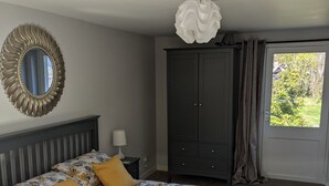 Ein Schlafzimmer mit Bett, Kleiderschrank, Spiegel und einem Fenster mit Vorhängen.