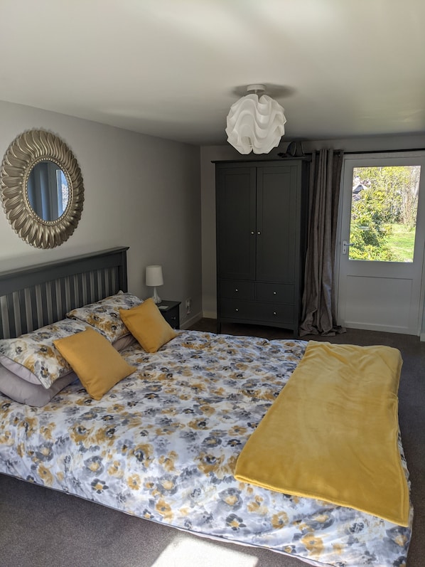 Un dormitorio con cama, armario, espejo y ventana con cortinas.